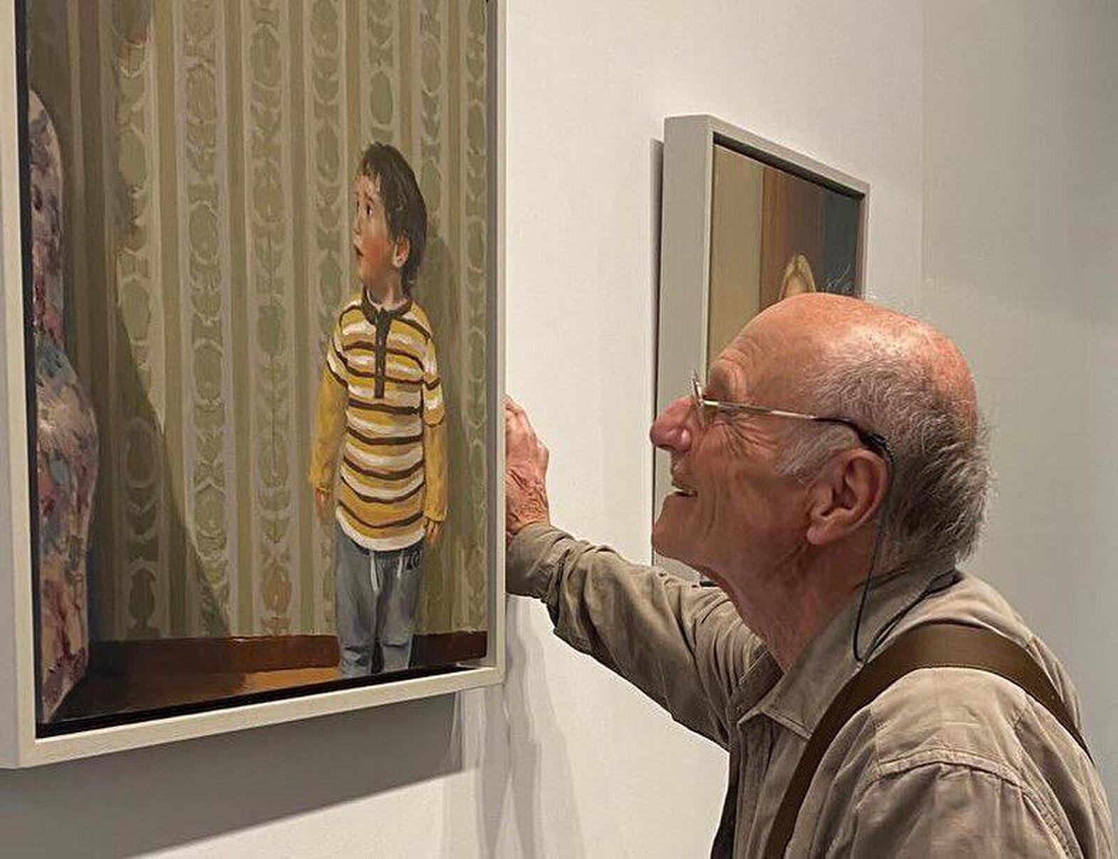 Un aficionado a la pintura sonríe ante uno de los cuadros de Baena.