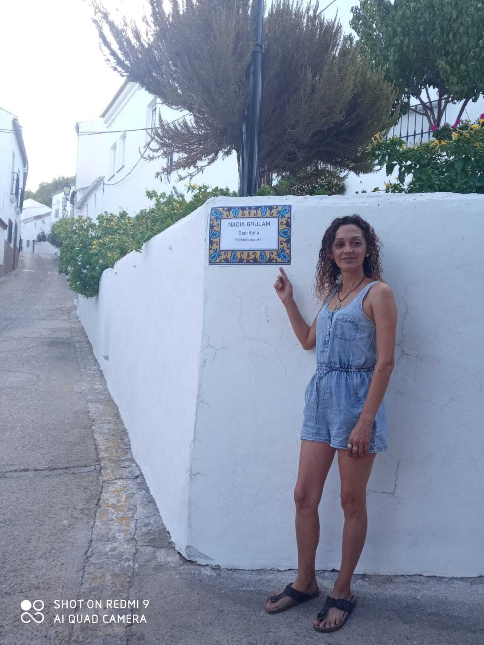 Una mujer de Algodonales muestra un cartel con el nombre de una afgana rotulando simbólicamente una calle.