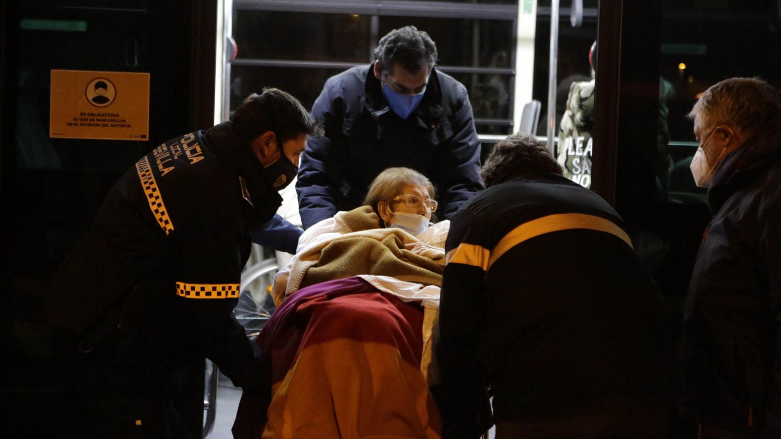 Agentes y familiares trasladan a una residente al autobús de Tussam que los llevaría temporalmente al Pabellón de San Pablo.