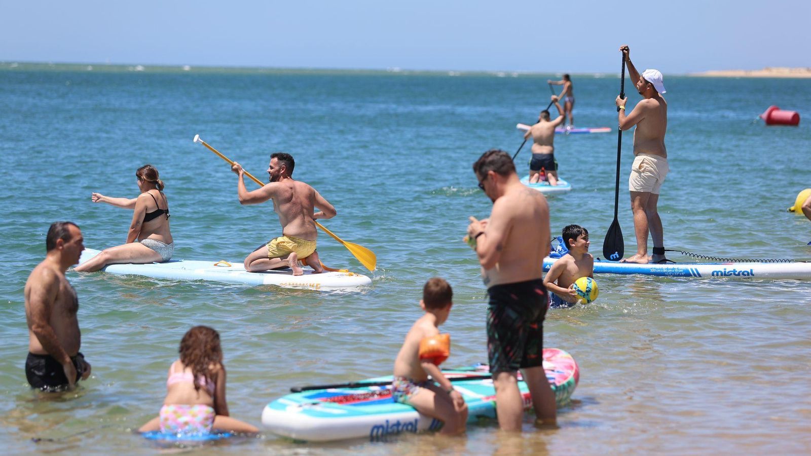 Varias personas con tablas de paddle surf en el agua.
