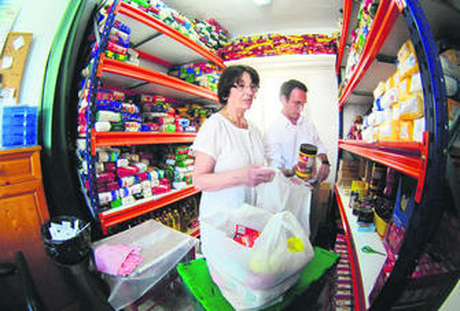 Voluntarios de Cáritas en la parroquia de Buen Pastor, preparando bolsas de víveres para repartirlas entre las familias acogidas.