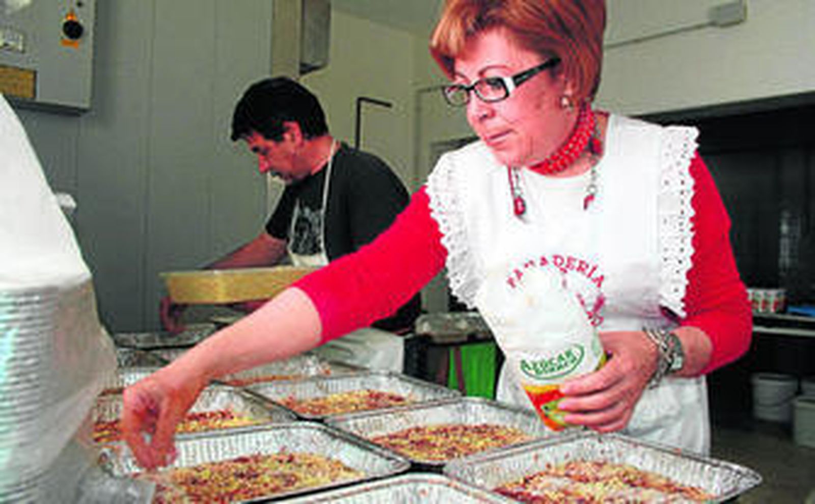 Mujeres elaborando la torta de pascua y una pastelería de la costa onubense con cocas de almendra.
