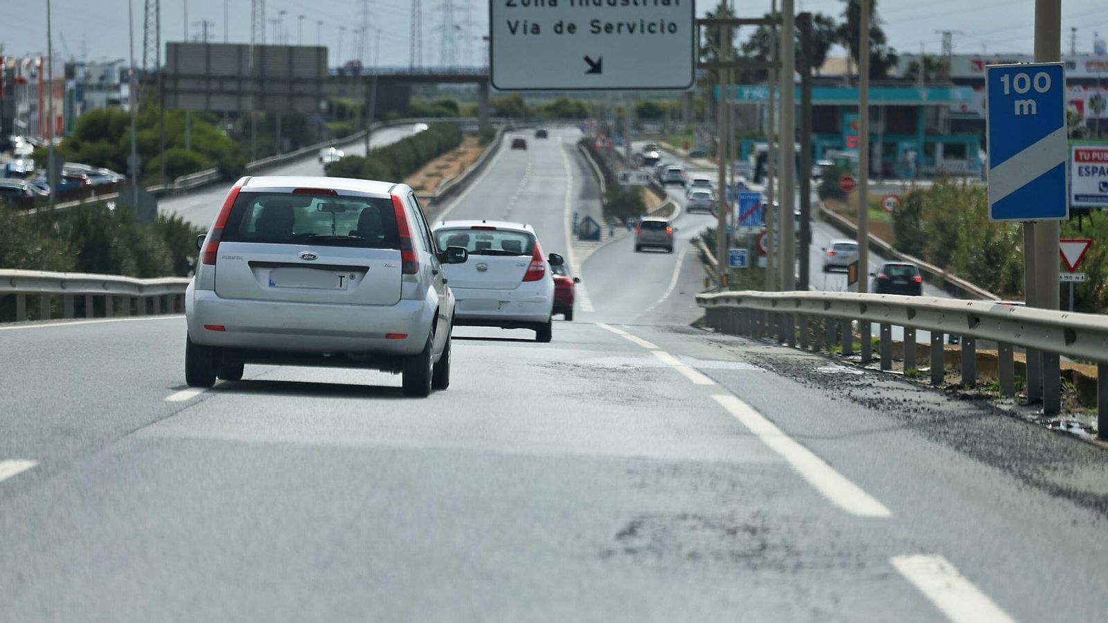 Varios coches circulan por una carretera de Huelva que presenta desperfectos.