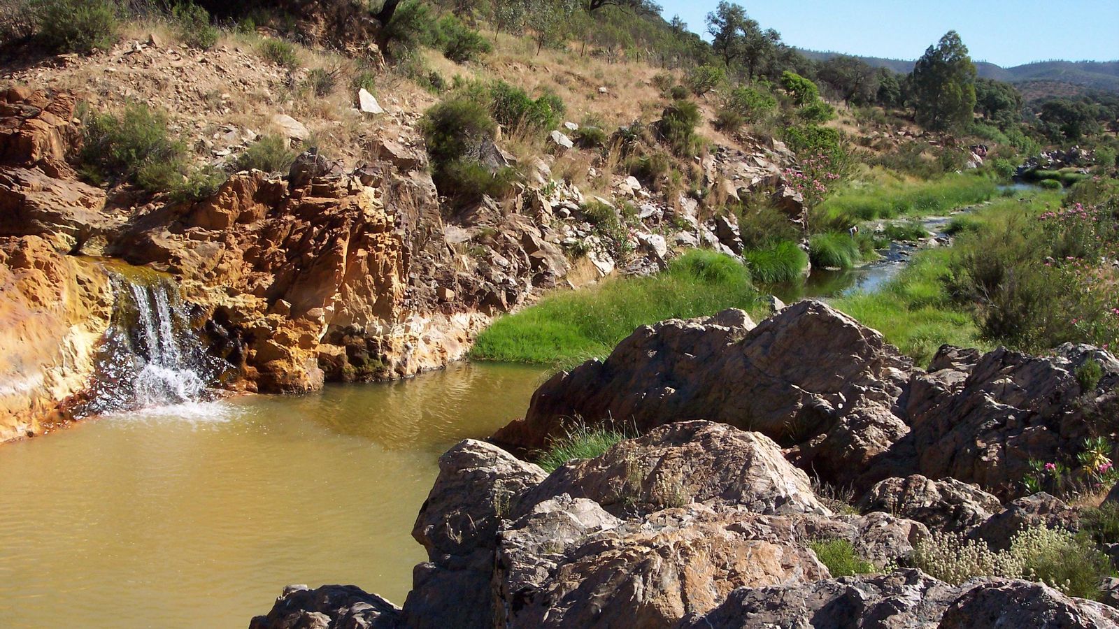 El río Odiel a su paso por Mina Concepción, que dejó de explotarse en 1987. Puede observarse el característico color rojizo de la oxidación, que contrasta con el verde de aguas arriba.