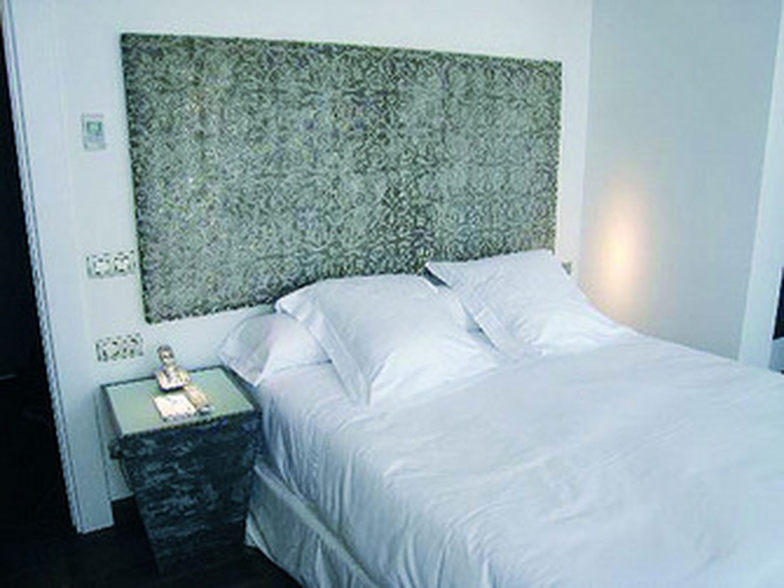 Una cama en una habitación de hotel con las sábanas limpias y cambiadas.