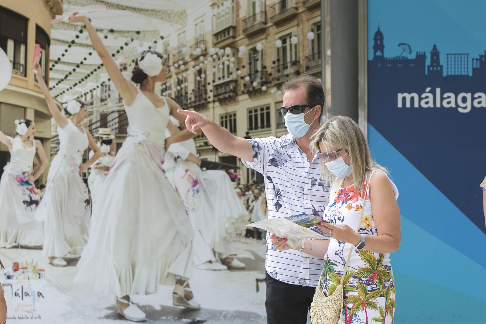 Dos turistas consultan un folleto de visita a Málaga.