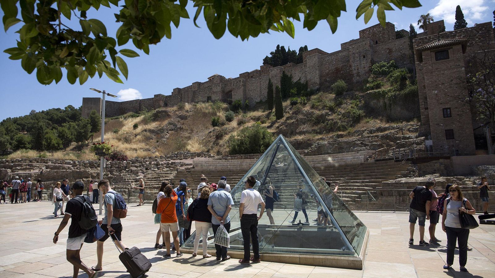 Visitantes en la calle Alcazabilla de la capital malagueña, con el Teatro Romano al fondo y la Alcazaba.