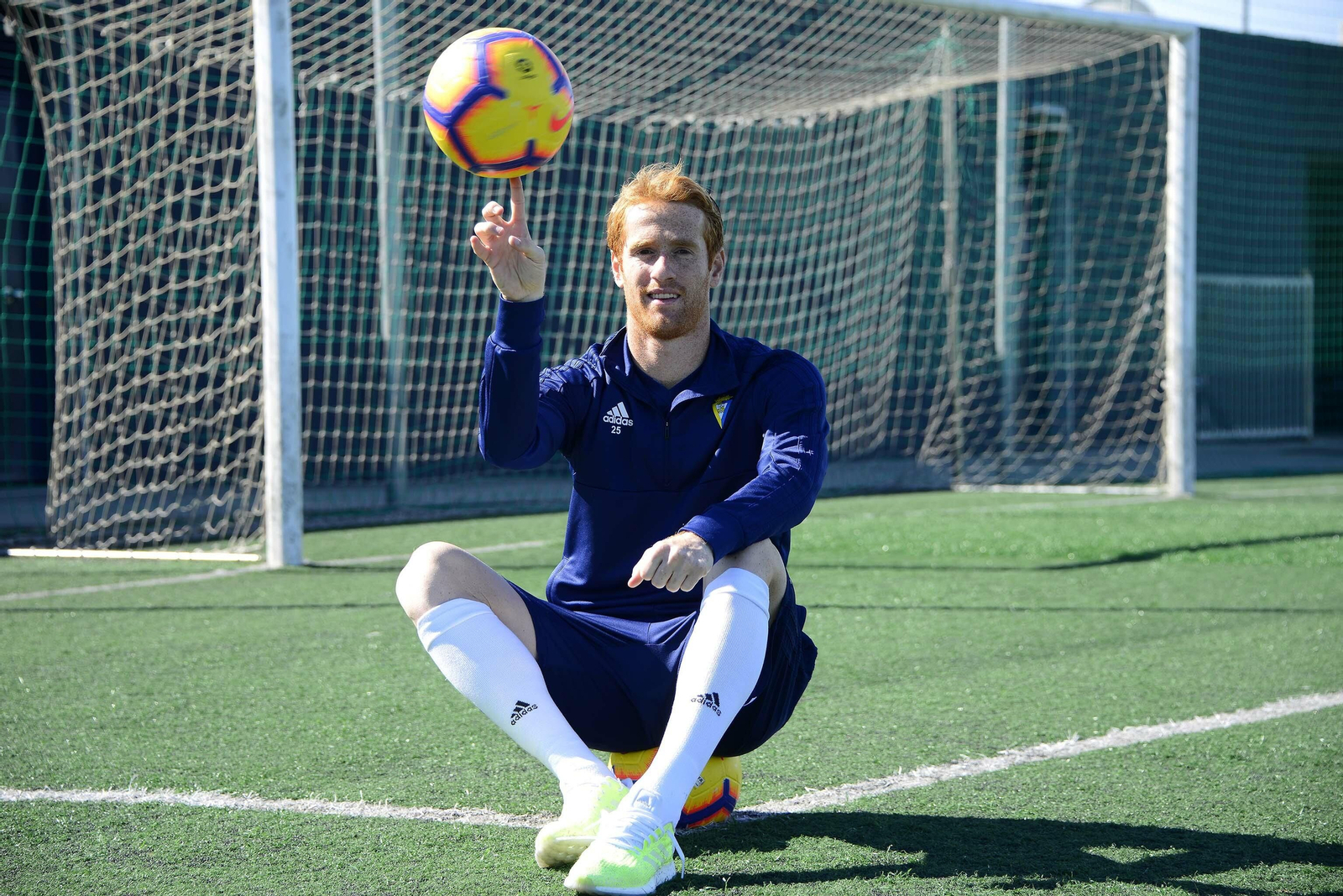 Álex juega con un balón mientras posa sentado sobre otro.