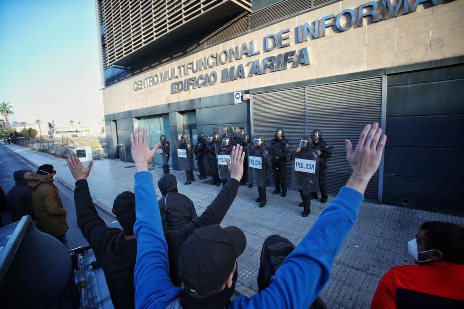 Manifestantes ante la sede de la Confederación de Empresarios de Cádiz, protegida por la Policía.
