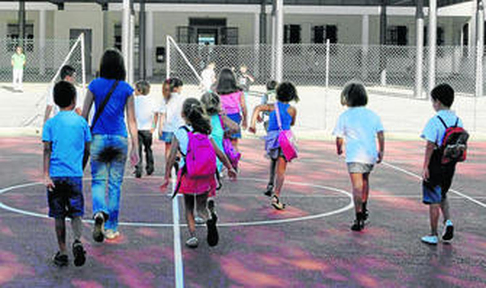 Un grupo de niños accede a las instalaciones de un centro educativo en compañía de una maestra.