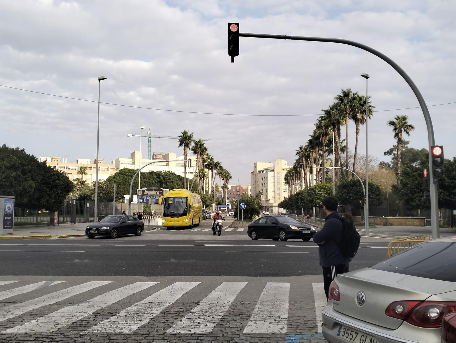 Un coche y una moto giran en sentido salida de la ciudad al llegar al cruce de la Transversal con la Avenida principal de Cádiz.