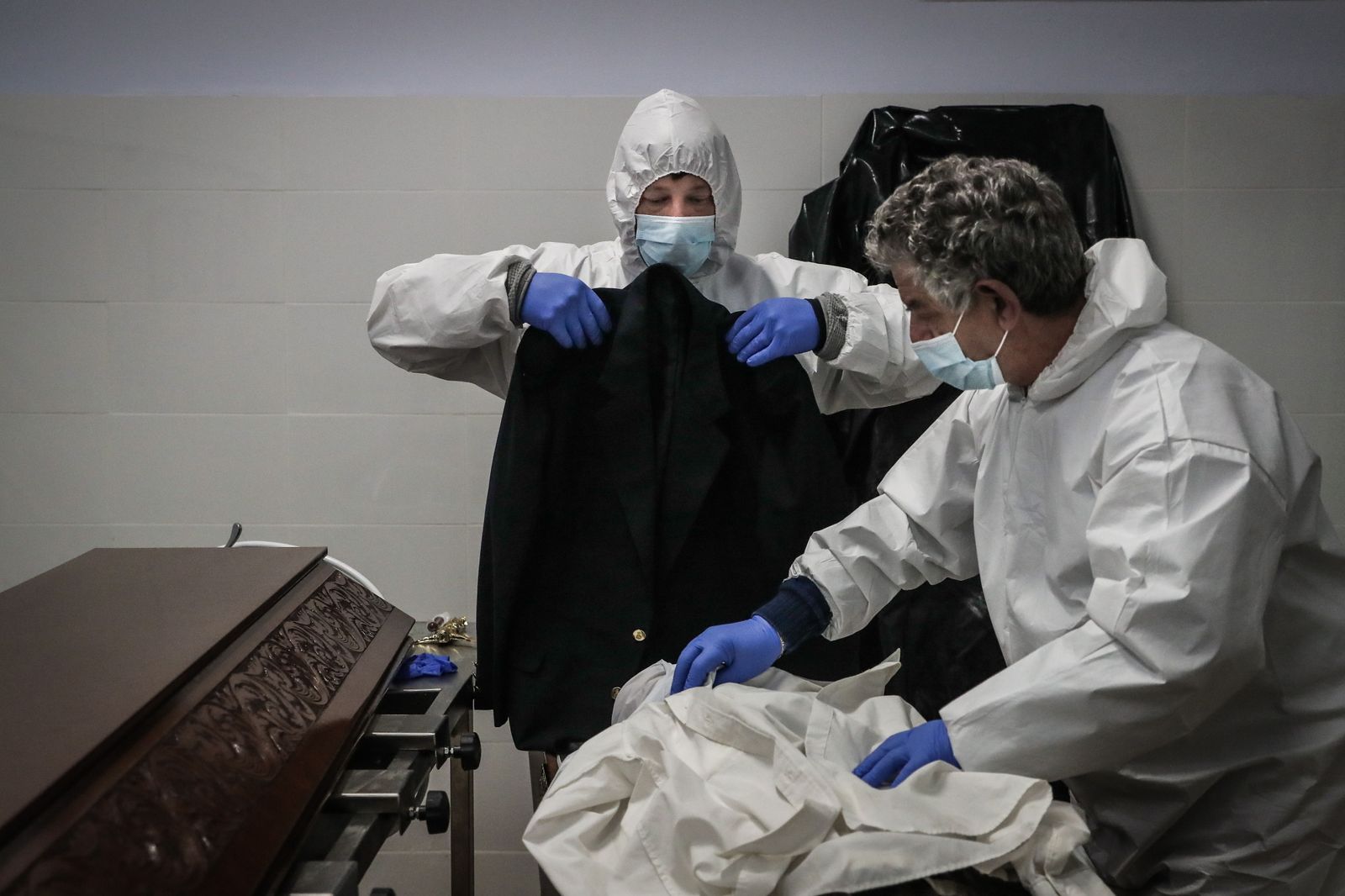 Dos trabajadores de una funeraria preparan a una víctima del covid en la localidad portuguesa de Amadora.