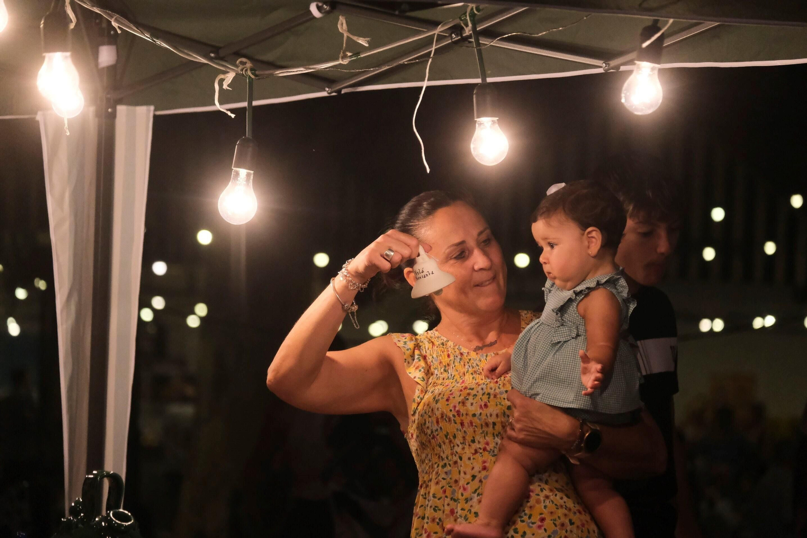 Una niña disfruta con el sonar de una campanita típica de la Velá.