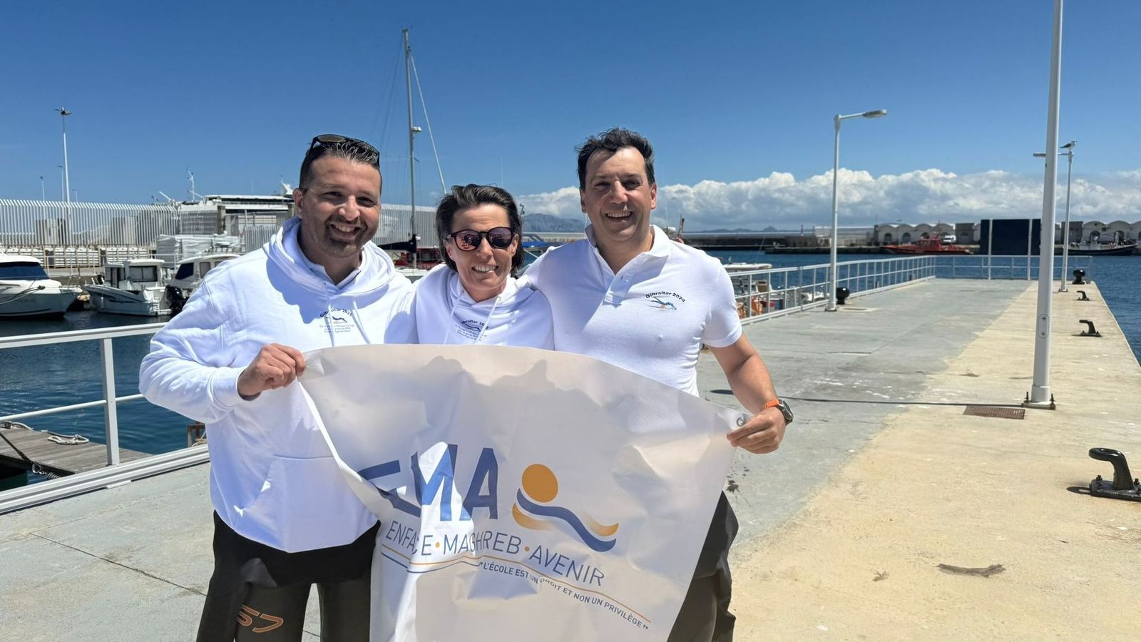 Los tres nadadores franceses, con una bandera de EMA en Tarifa.
