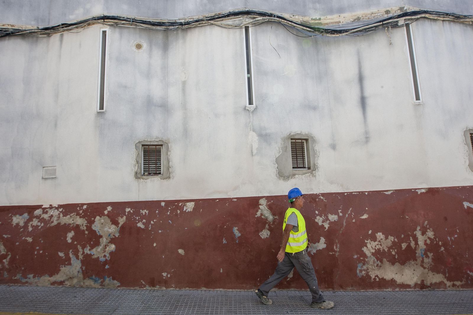 Un operario pasa junto a la fachada del Mercado de San Antonio, que aún soporta el excesivo cableado.
