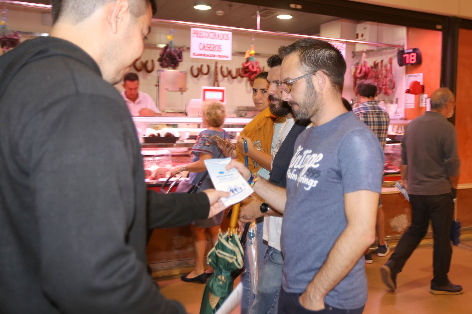 Un voluntario reparte folletos informativos en el Mercado de Abastos