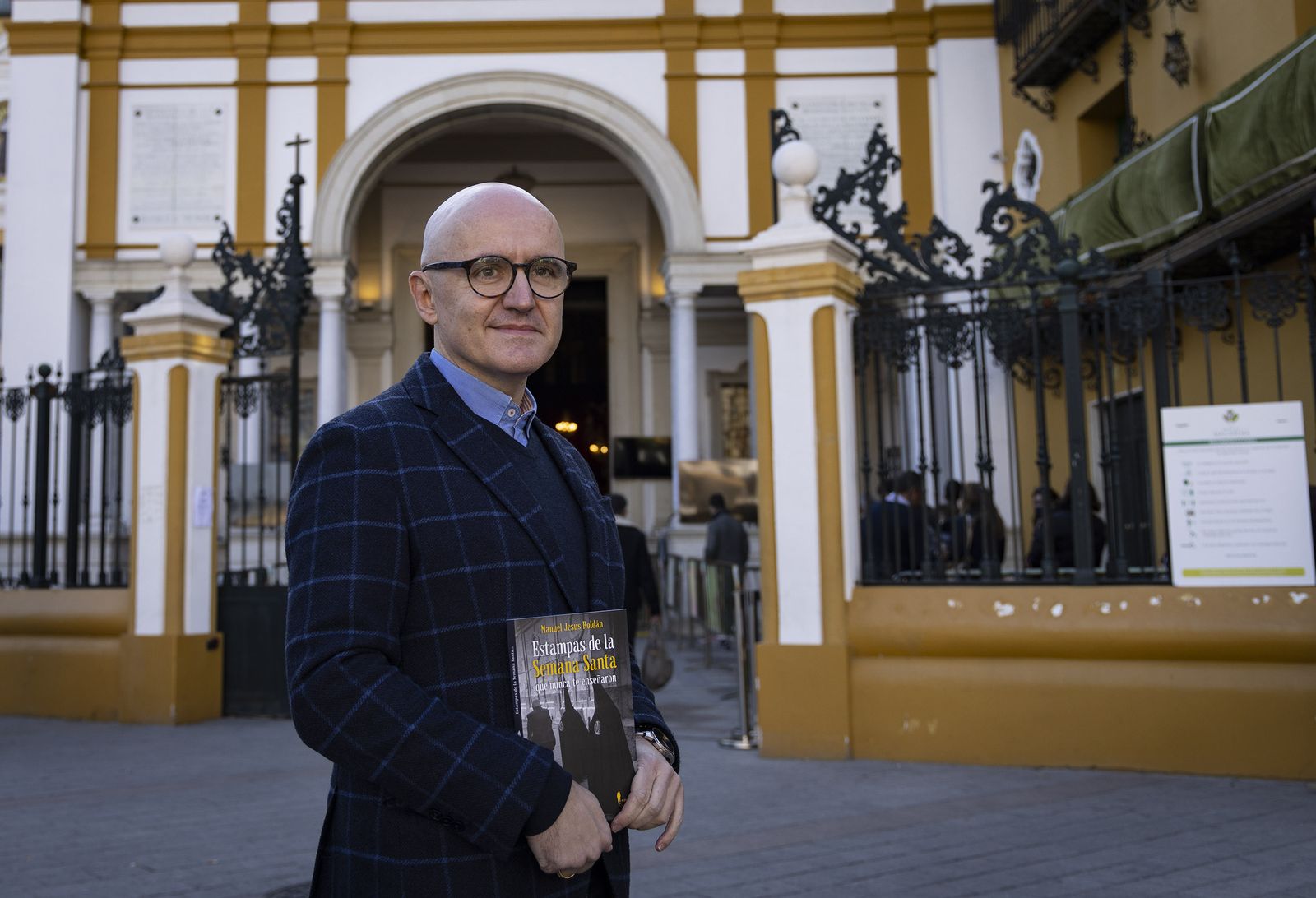 Manuel Jesús Roldán sostiene un ejemplar de su libro junto a la Basílica de la Macarena.