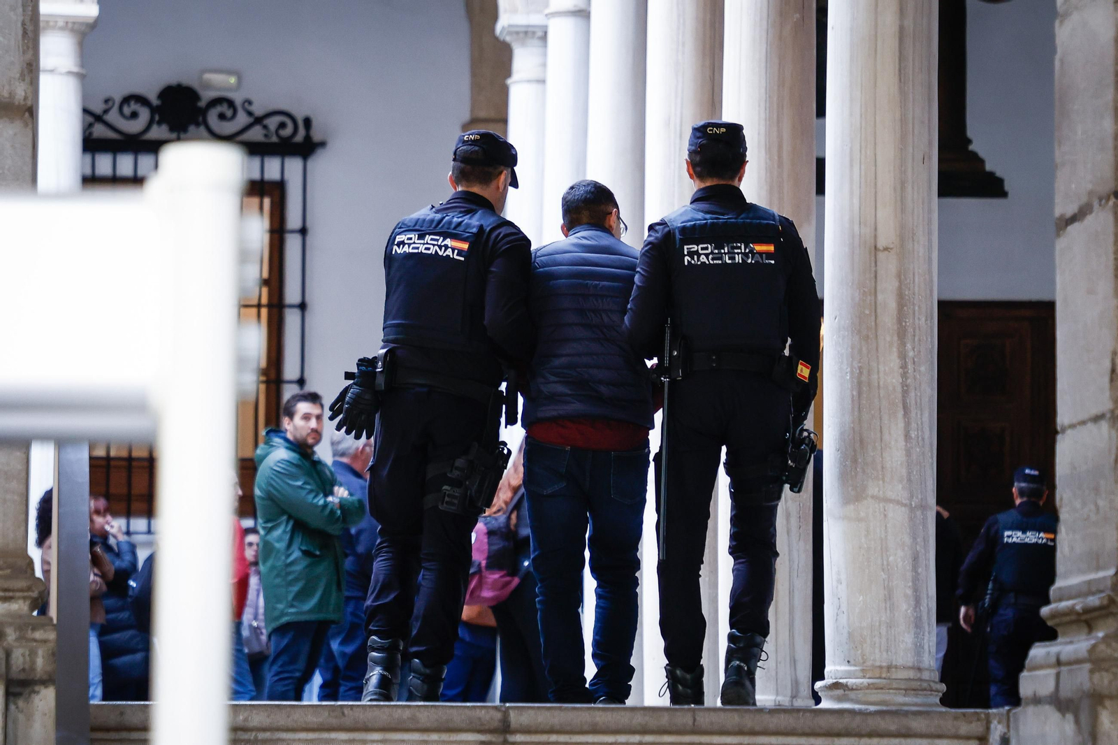 Dos agentes de la Policía Nacional escoltan a uno de los acusados en la primera jornada del juicio.