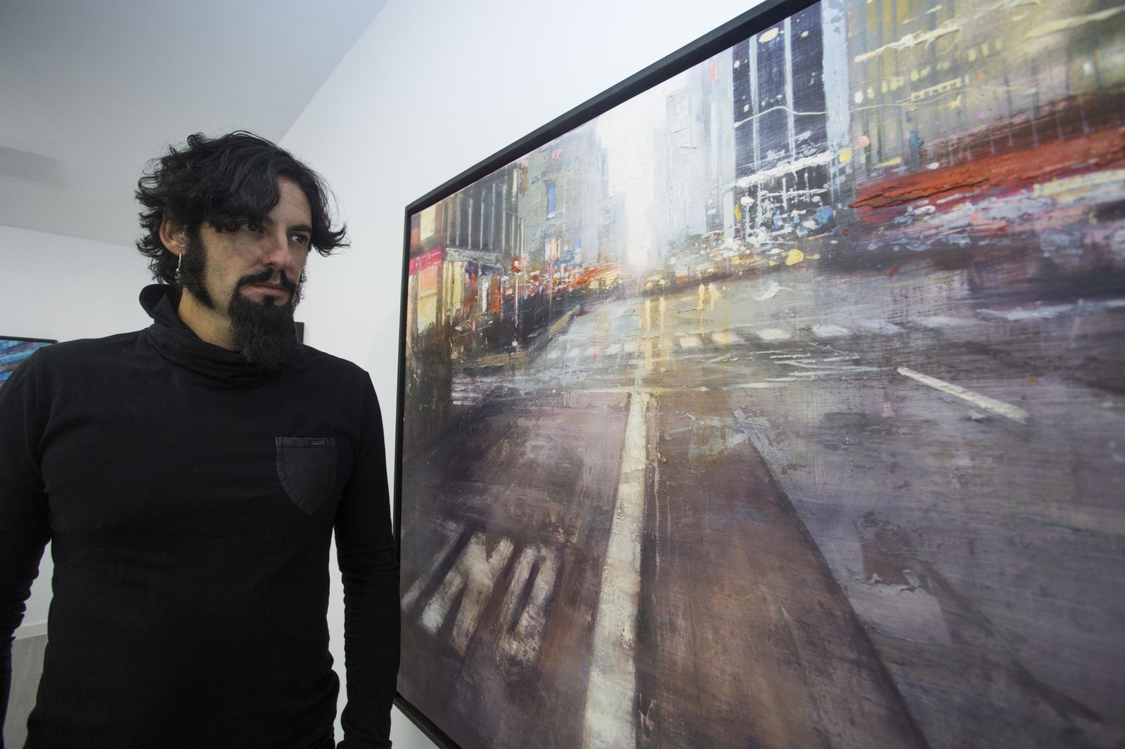 El creador posa junto a una de sus pinturas, en que la recrea la magnética nocturnidad de Manhattan.