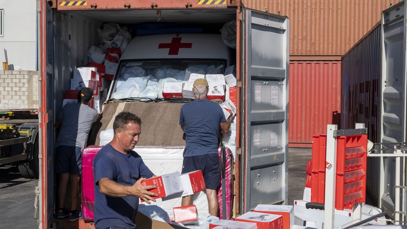 Unos colaboradores cargan otro de los 'containers'.