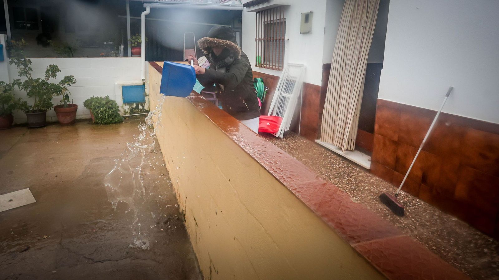 Fátima, vecina desalojada de La Corta, achica agua ayer en el patio de su vivienda.