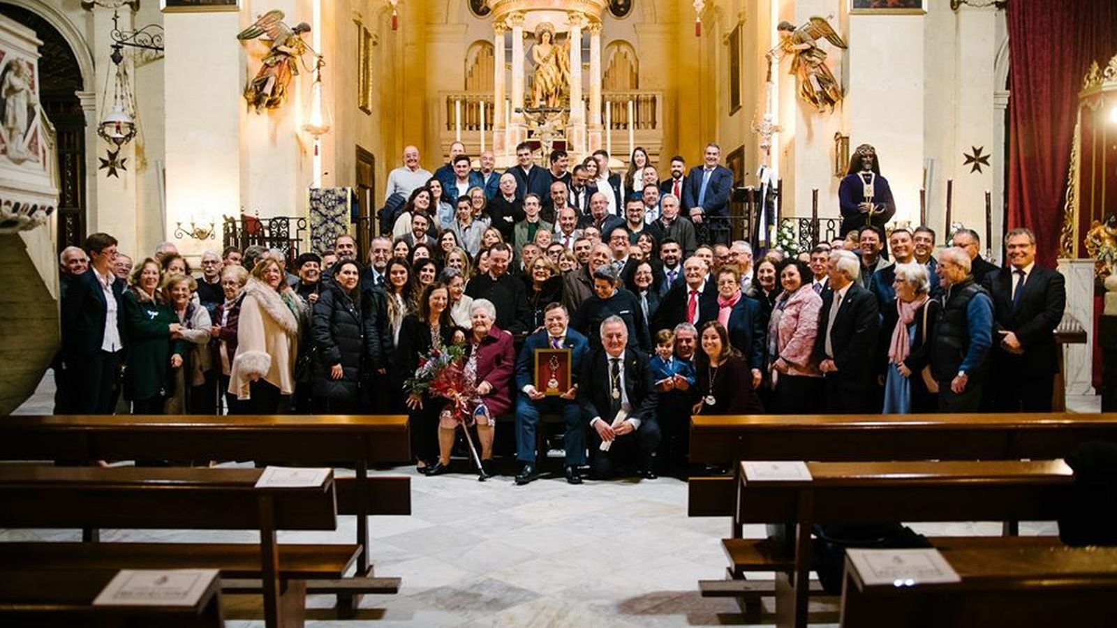 El homenajeado posa con los asistentes al acto ante el altar mayor de la Iglesia de San Juan Bautista.