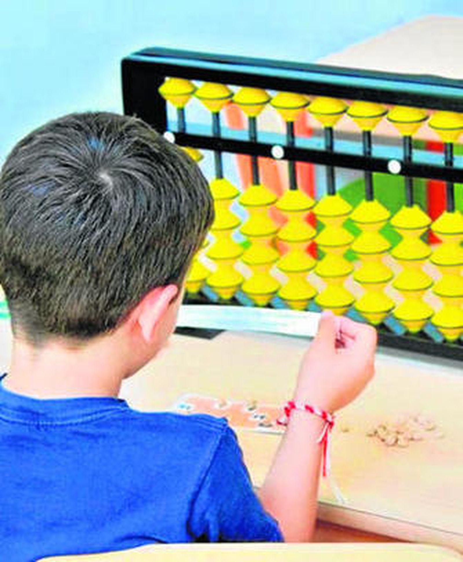 Un niño utilizando un ábaco en el aula de un centro educativo.