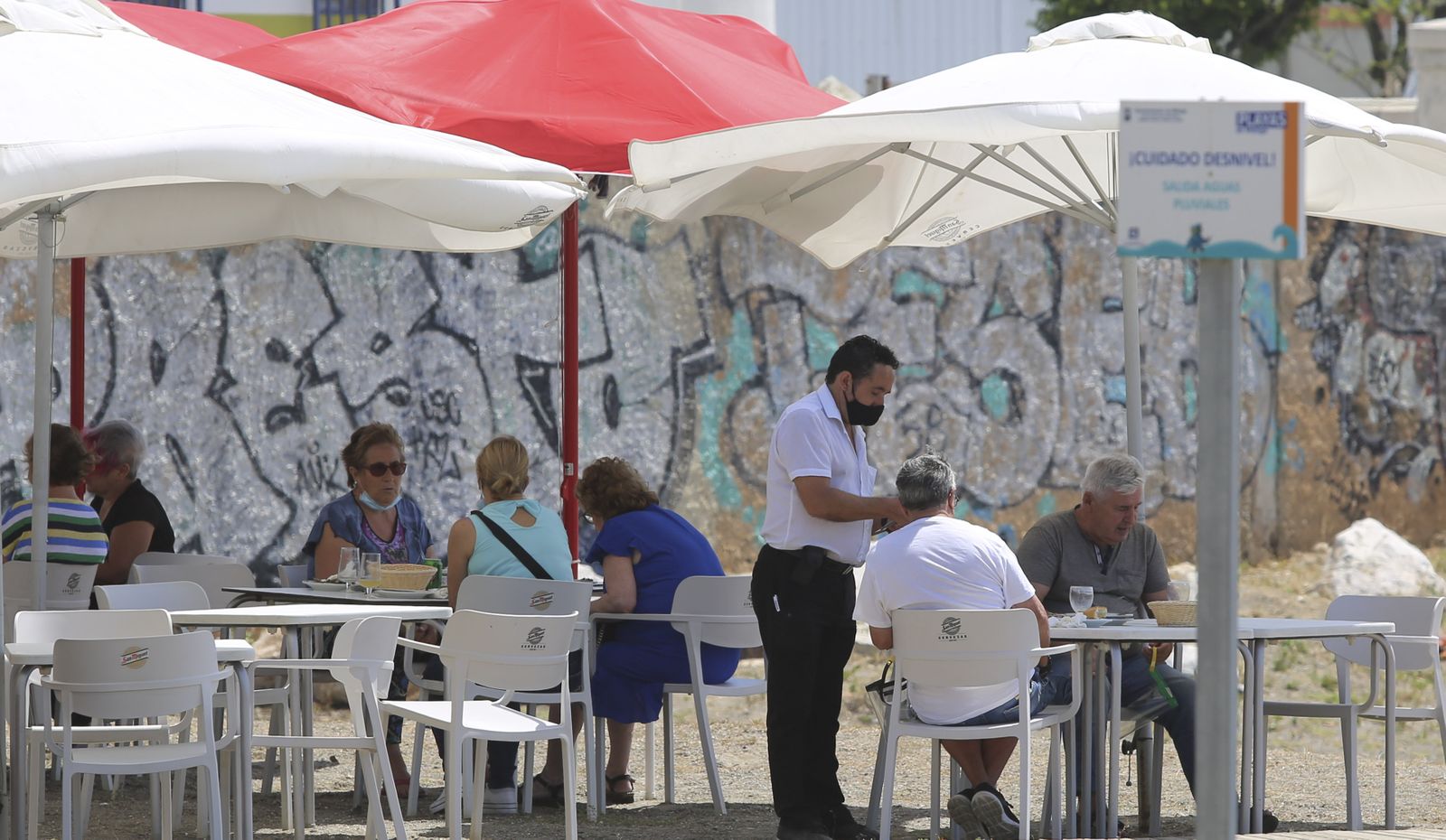 Un camarero atiende a unos clientes en la terraza de un bar de Málaga.