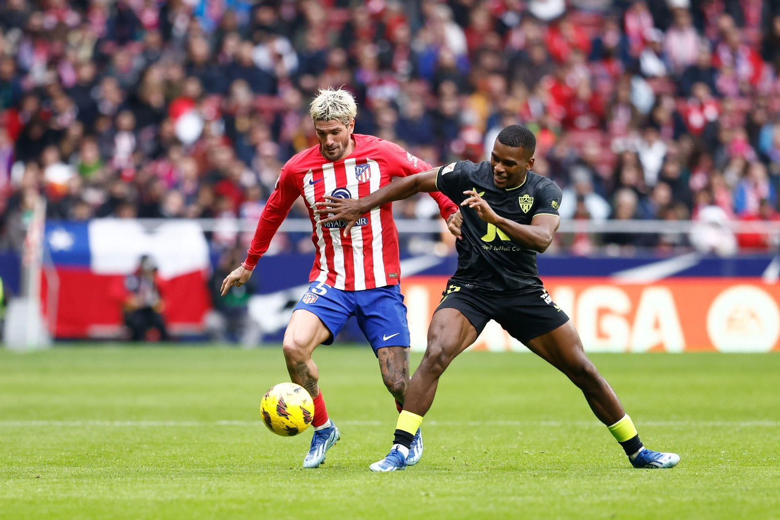 Sergio Akieme pugnando un balón con Rodrigo de Paul.
