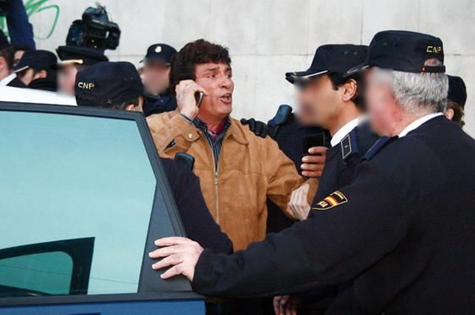 Juan Cortés, abuelo de Mariluz, habla por teléfono mientras detienen a su esposa, Mariluz, por tirar un paraguas a un furgón policial donde viajaba Rosa Del Valle.

Foto: Alberto Dom?uez