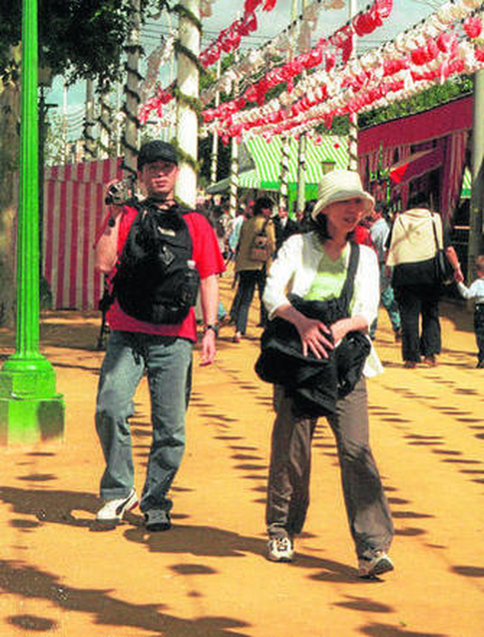 Dos turistas japoneses deambulan por el real de la Feria.