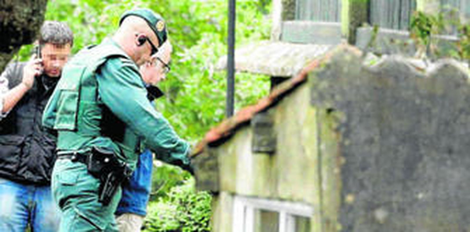 El padre de Asunta entra, custodiado por la Guardia Civil, en la casa de Teo durante el registro del viernes.