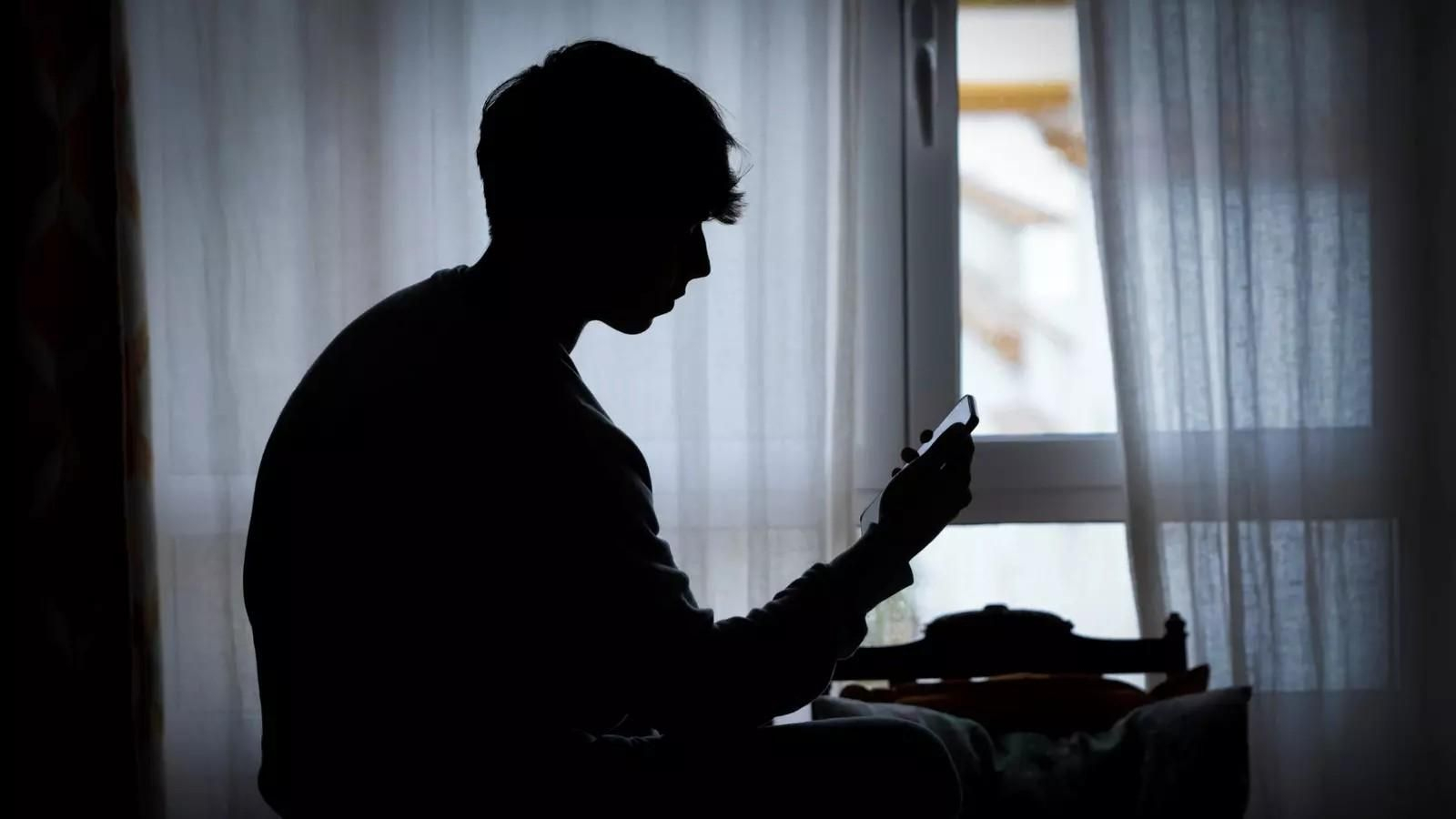 Un joven mira su móvil