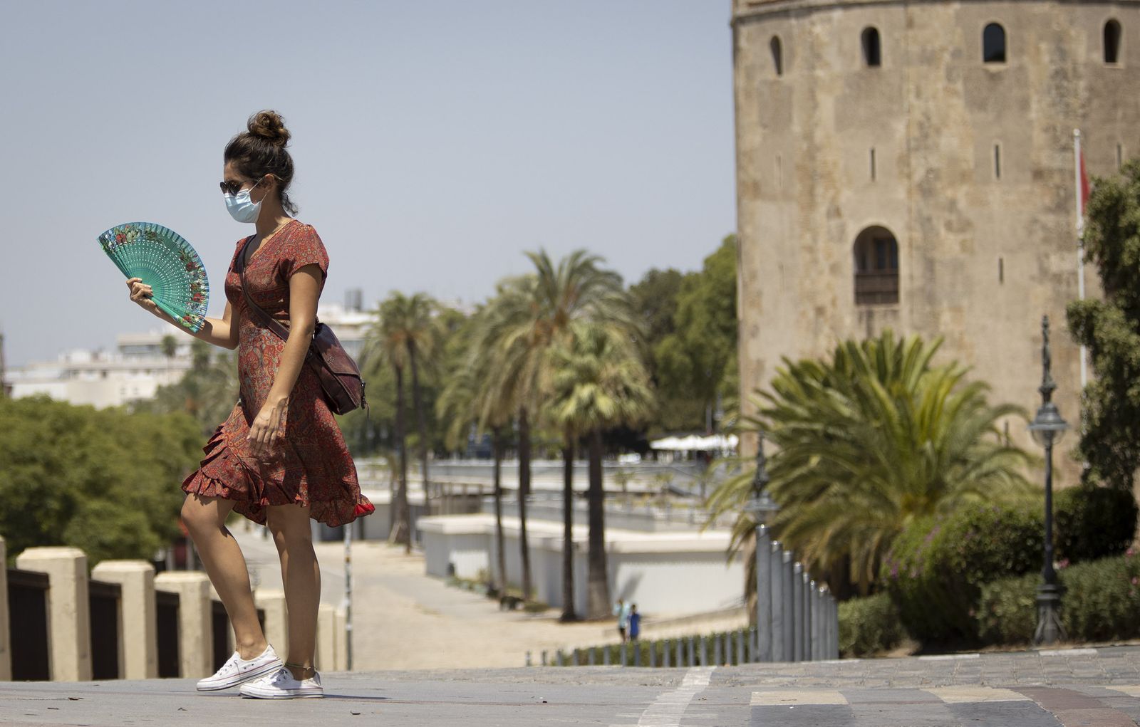 Una joven con mascarilla pasea cerca de la Torre del Oro.