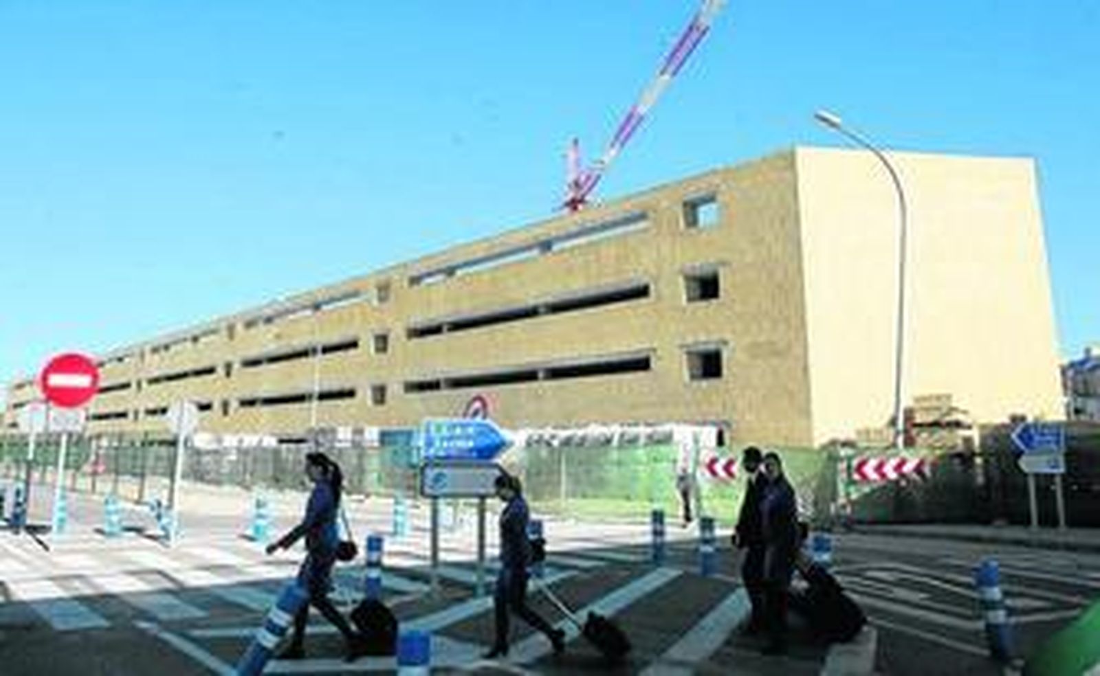 Miembros de una tripulación pasan por delante del edificio, aún en obras, del nuevo parking de San Pablo.