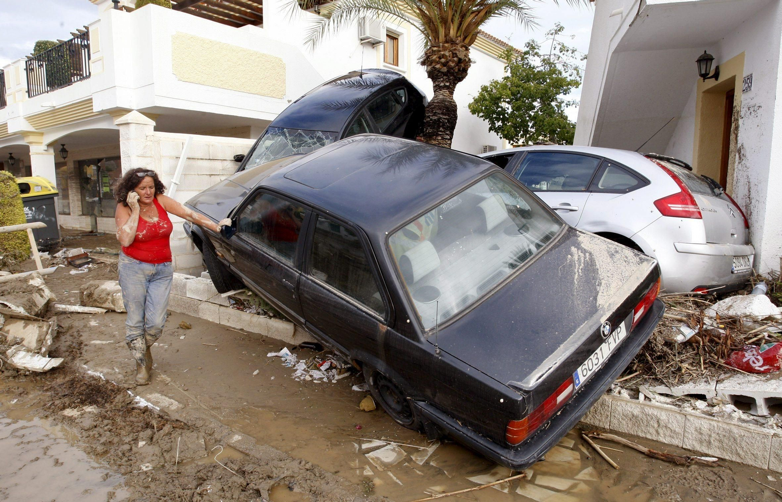 Una mujer junto a varios vehículos siniestrados en la localidad almeriense de Vera , tras las fuertes lluvias.