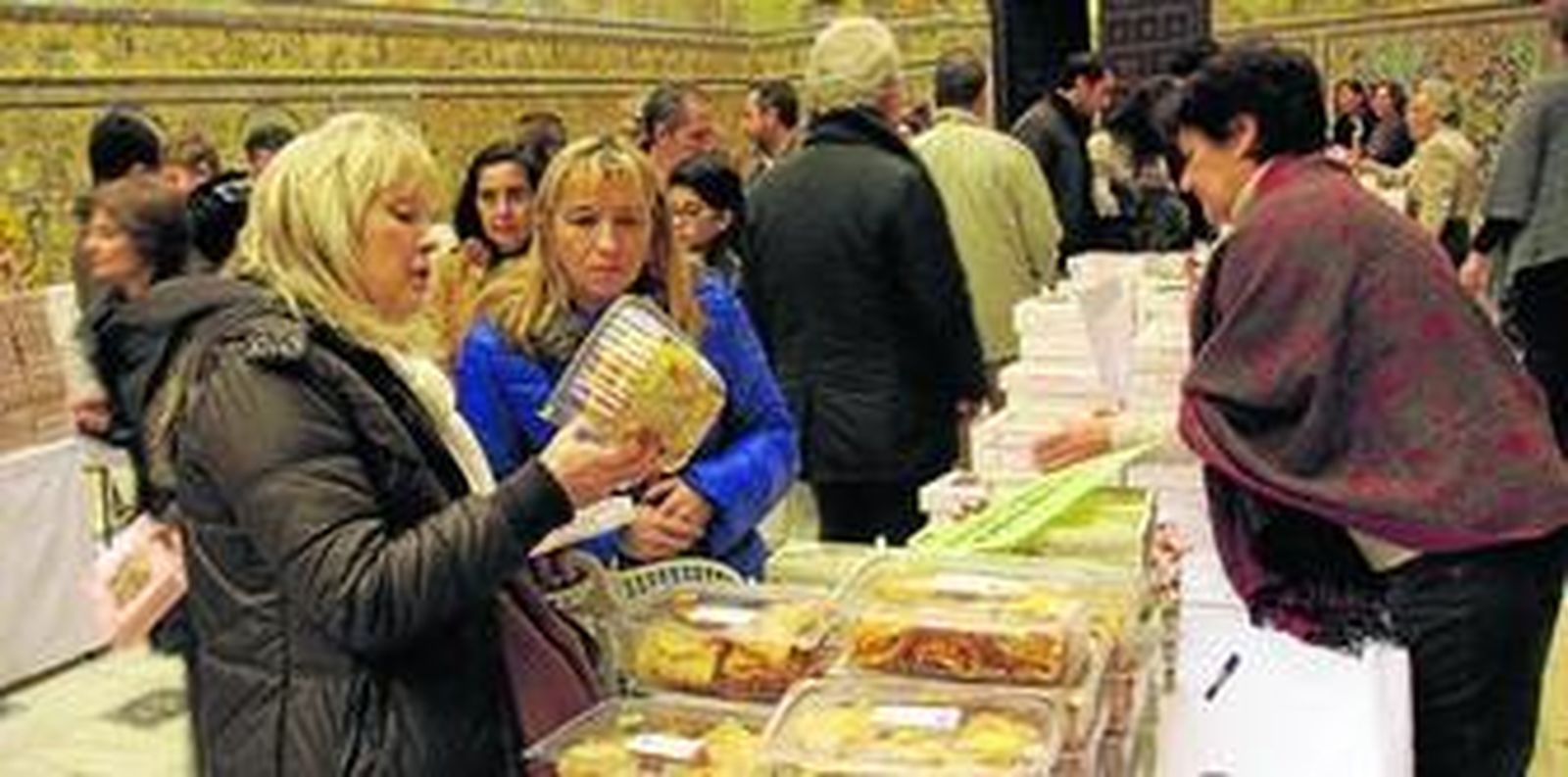 1. Dos mujeres eligen entre la gran variedad de productos de esta Muestra de Dulces de Conventos de Clausura. 2. El puesto de las jerónimas de Constantina destaca por sus productos de chocolate.
