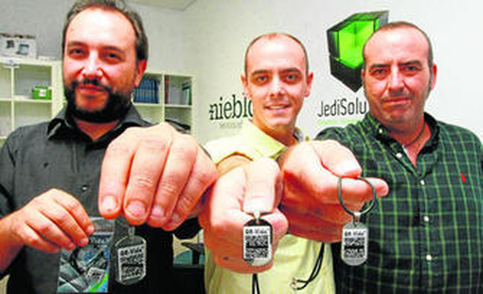 Los onubenses Rafael Pérez (izquierda), José Luis Martín y Chencho Forcén, creadores de QR-Vida, con los colgantes que portan los códigos.