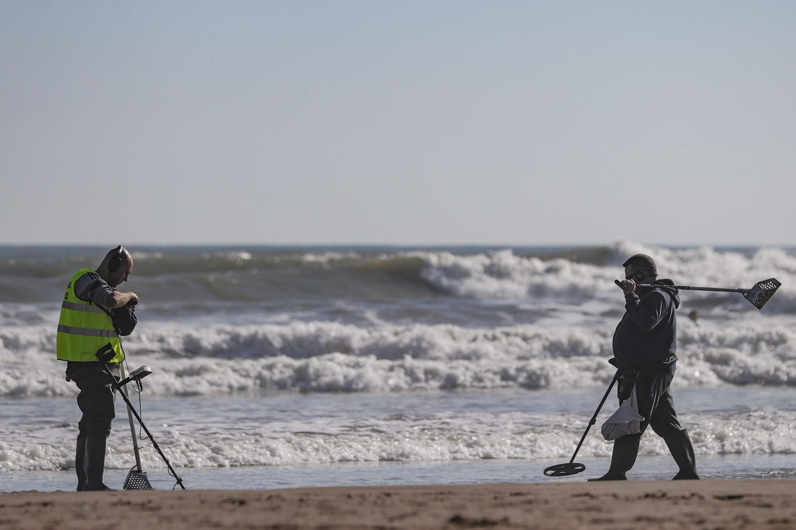 Dos personas rastrean una playa, en una imagen de archivo