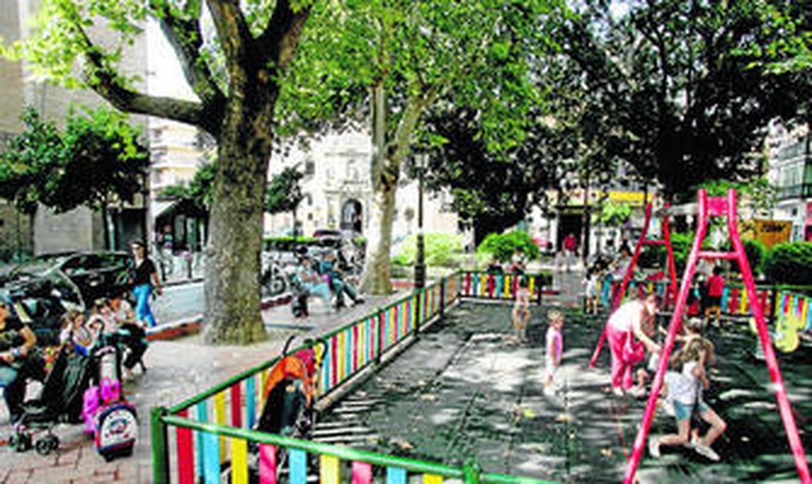 Los niños juegan en la zona central de la plaza Cristo de Burgos, rodeados de árboles.