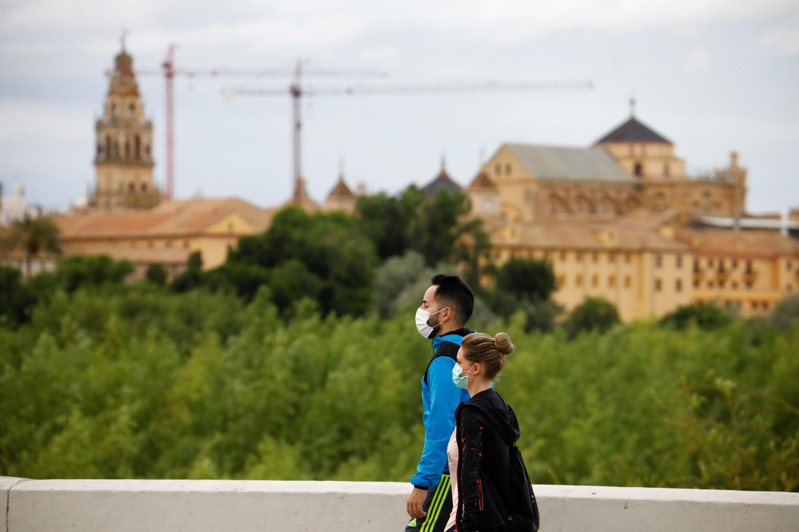 Una pareja pasea con mascarilla con la Mezquita de fondo.