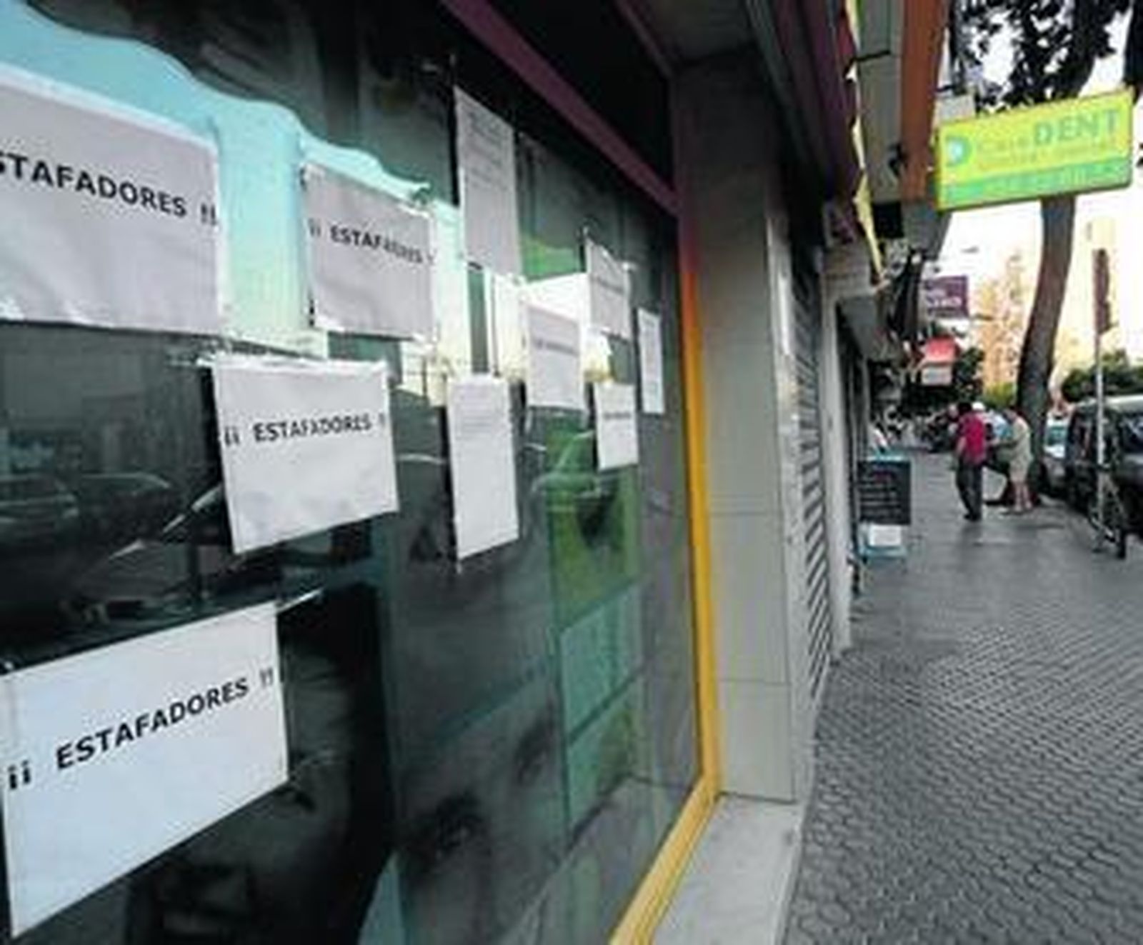 Carteles de protesta en el escaparate de la clínica dental Caredent Triana, cerrada sin previo aviso.