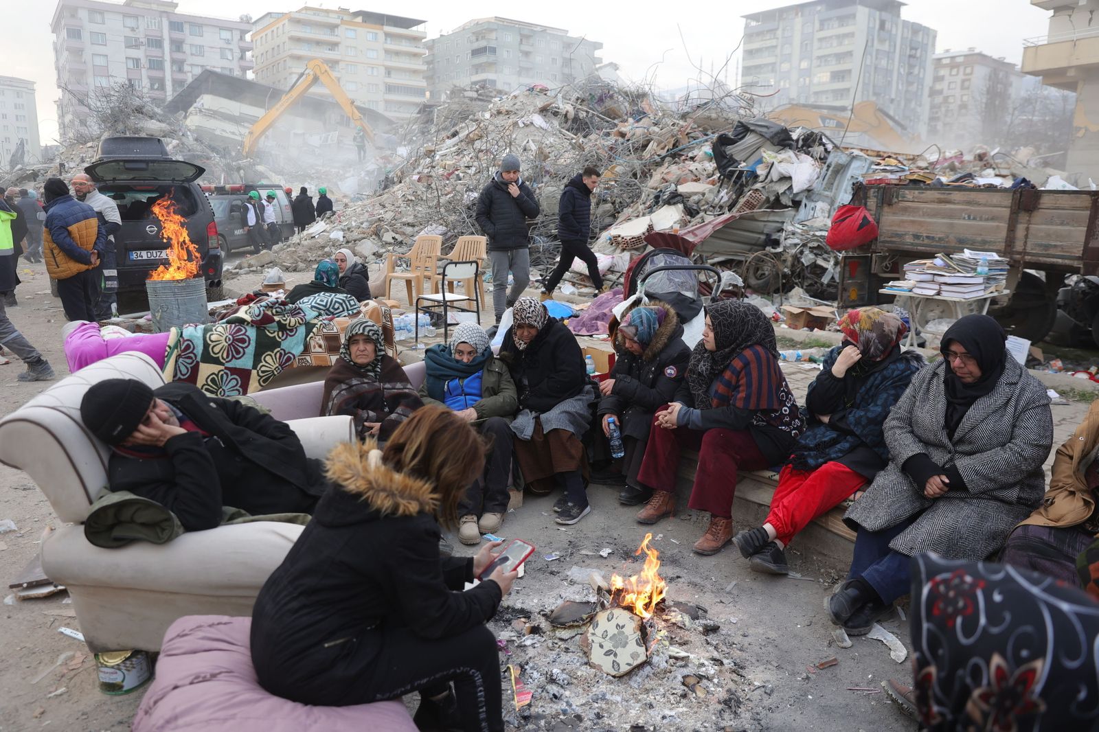 Un grupo se calienta alrededor de un fuego junto a los escombros de un edificio en una ciudad turca.