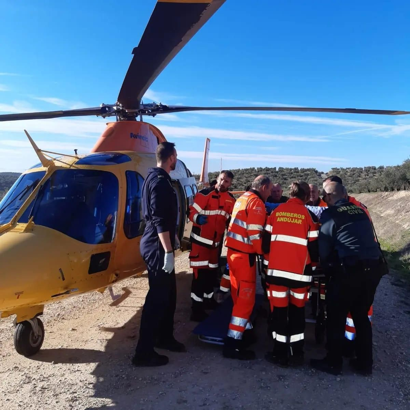 Miembros del Cuerpo de Bomberos de Andújar, junto a un helicóptero de rescate, en un accidente en la autovía.