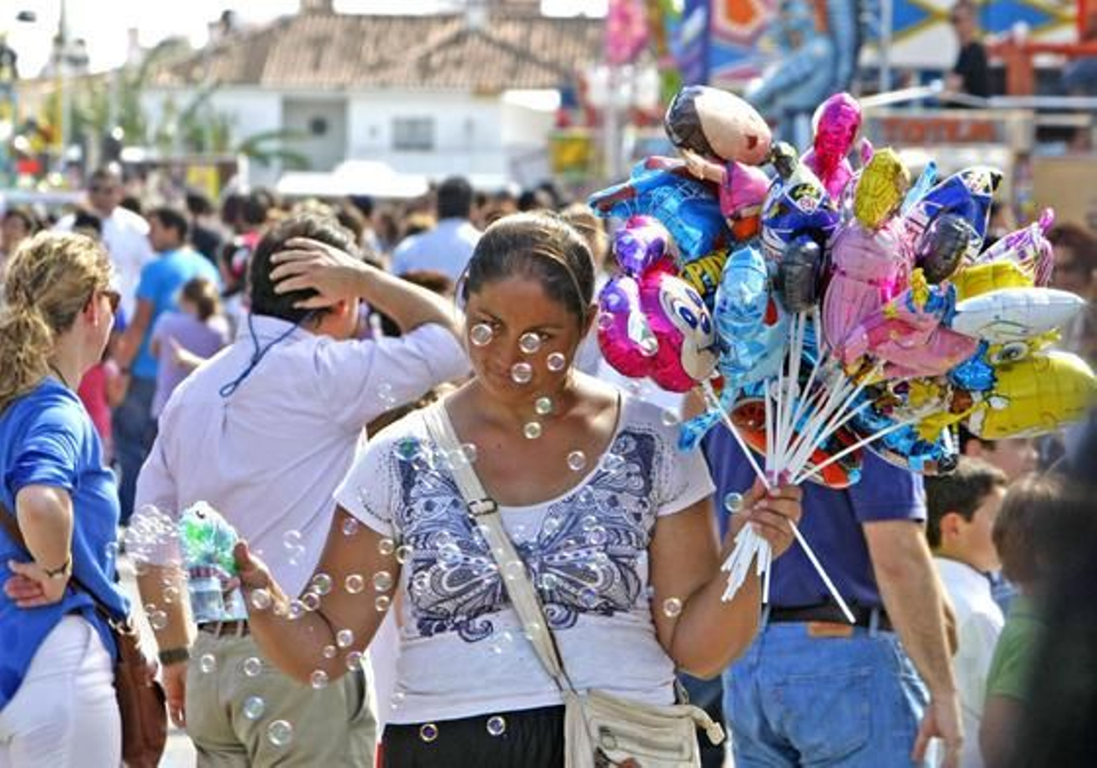 Mini regalos. Una señora vendiendo globos y pistolas de pompas de jabón, por la zona de las atracciones.

Foto: Pascual