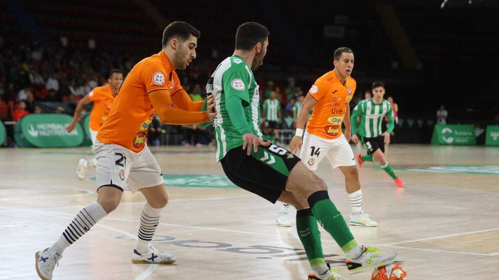 El bético Chano controla la posesión del balón presionado por un rival.