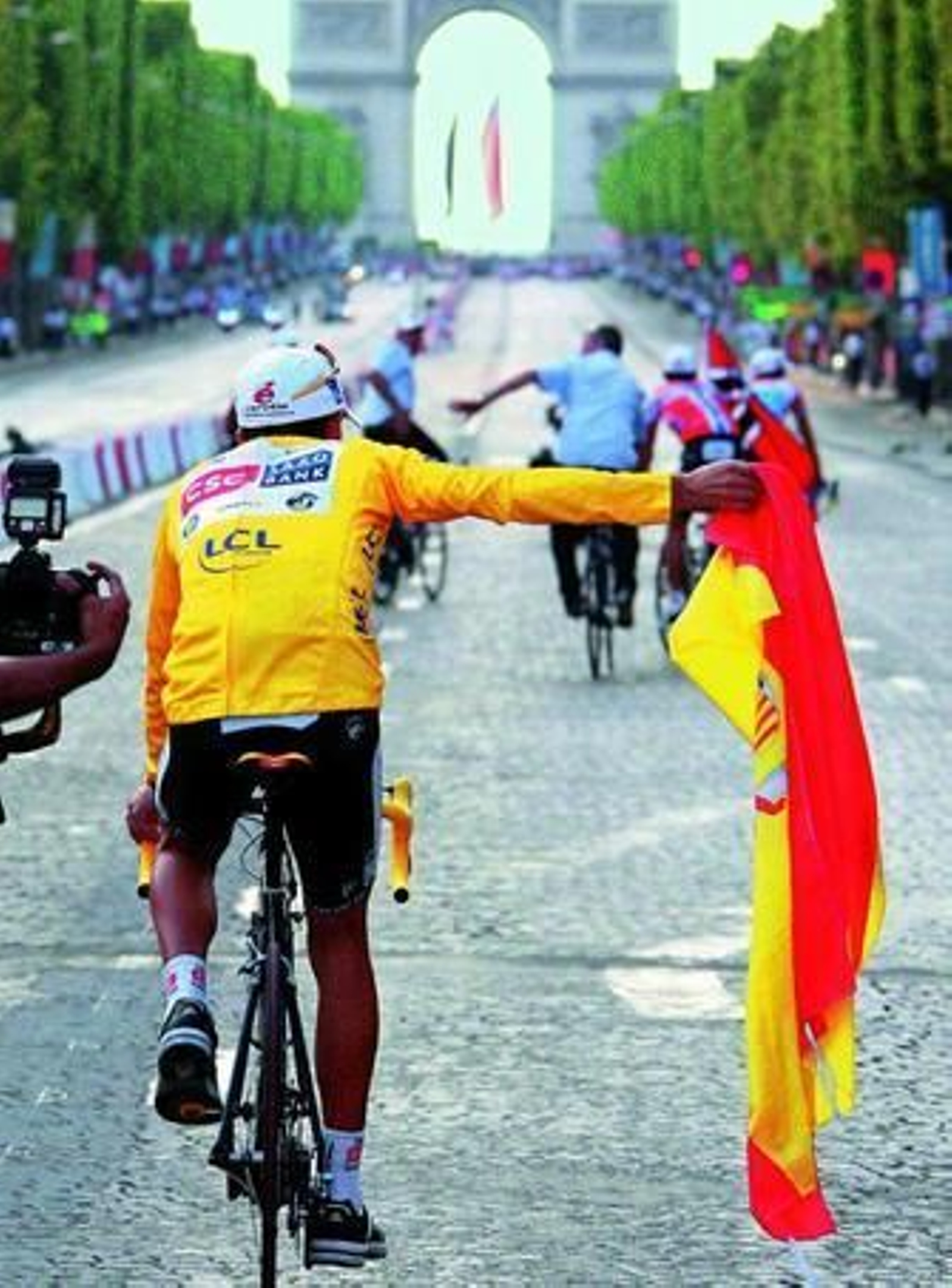 Carlos Sastre pasea la bandera de España por los Campos Elíseos de París.