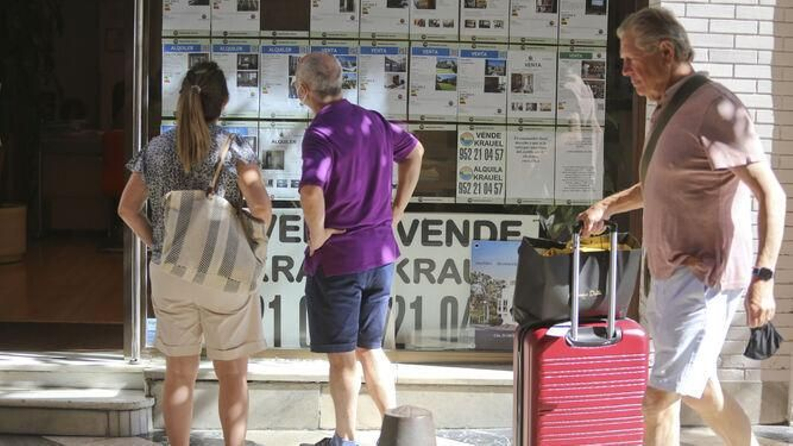 Dos personas observan el escaparate de una inmobiliaria en Málaga capital.