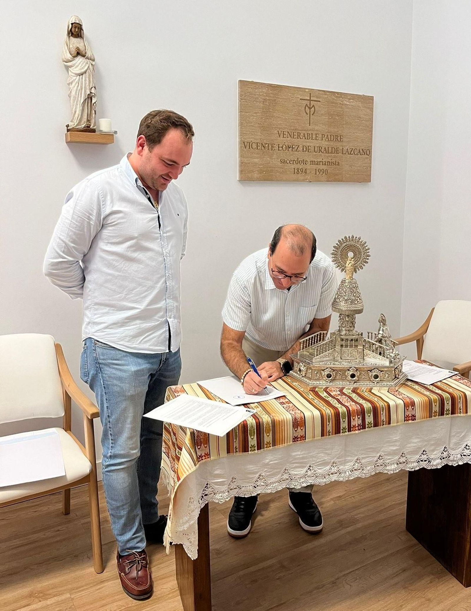 El marianista Rafael Iglesias firma el acta de donación de las reliquias en presencia del hermano mayor, Javier Trías.