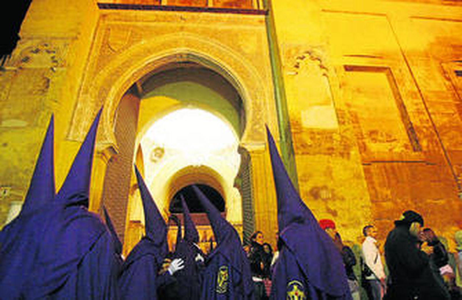 Varios nazarenos a su paso por la Puerta del Perdón de la Mezquita Catedral.